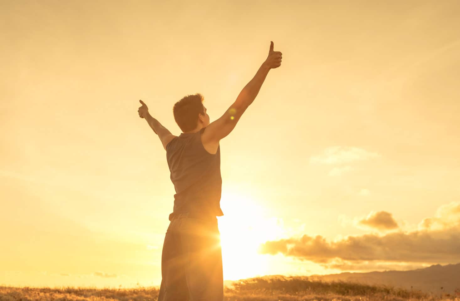 Man with arms in air outdoors.